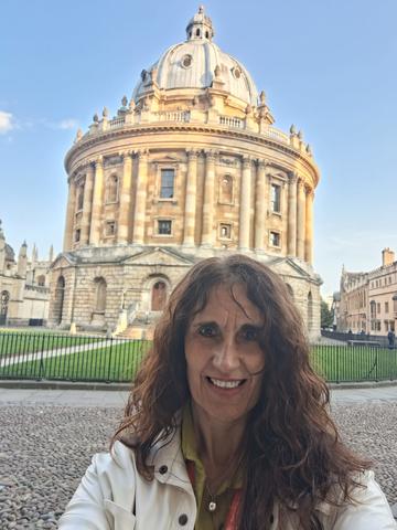 Sandra stands in front of the Radcliffe Camera building on a sunny day