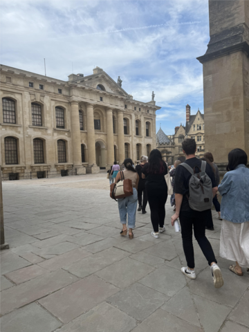 A group of people walking across a quad towards one of the Bodleian Libraries buildings