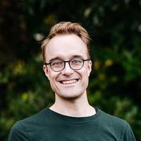 James Baker smiling wearing glasses